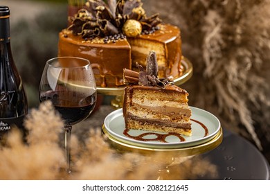 Chocolate Layer Cake With Fancy Chocolate Decoration Served With A Glass Of Wine