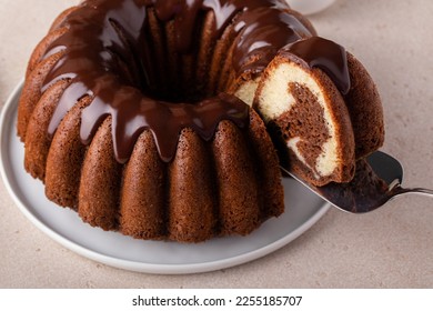 Chocolate marble bundt cake or zebra cake with chocolate glaze drizzled on top with a slice taken out