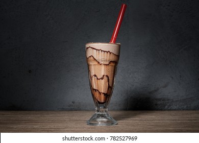 chocolate milkshake against grey background and brown wood table top