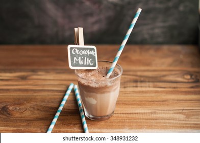 Chocolate Milkshake On A Wooden Background With Paper Straw And Chalkboard Clips With Text Written And Against Chalkboard Background 