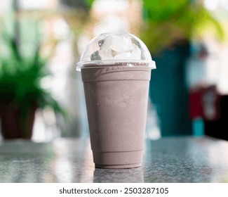 A chocolate milkshake topped with whipped cream is displayed on a table, surrounded by greenery in a relaxed setting. - Powered by Shutterstock