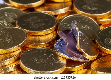 Chocolate Money Pile Of Gold Coins. Edible Sweets Covered In Foil As Pretend Money. One Open Coin Half Eaten
