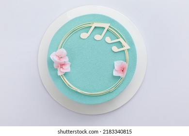 Chocolate Mousse Cake On A White Background, Decorated With Flowers And Notes Of White Chocolate. Cake For A Musician Birthday. Top View. Turquoise Mousse Cake.