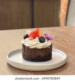 Chocolate mousse with chocolate cookies crumble based. Topped with fresh cream, blueberries and strawberries. Decorated with edible flowers. Dish on wooden table. - Powered by Shutterstock