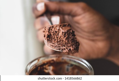 Chocolate Mousse Dessert Isolated On White Background On The Spoon Texture Close Up In African American Hand