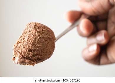 Chocolate Mousse Dessert On White Background On The Spoon Texture Close Up In African American Hand 