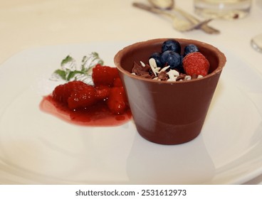 Chocolate mousse in a pot made of chocolate with fresh berries and fruit on a white plate with space for text - Powered by Shutterstock