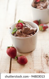 Chocolate Mousse Topped With Mint Leaf And Strawberries In A White Cup