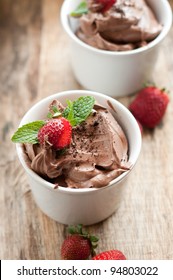 Chocolate Mousse Topped With Mint Leaf And Strawberries In A White Cup