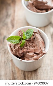 Chocolate Mousse Topped With Mint Leaf And Strawberries In A White Cup