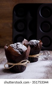 Chocolate muffin in baking paper on a wooden background. Selective focus.