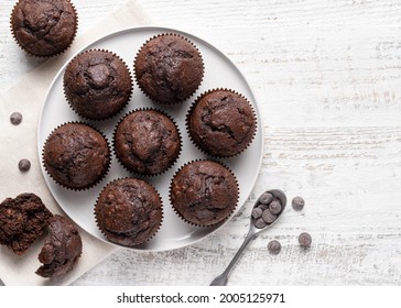 Chocolate muffins on white ceramic plate. Homemade fluffy and moist chocolate cakes. Top view. Copy space. White wooden table background. - Powered by Shutterstock