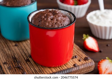 Chocolate Mug Cake With Whipped Cream And Fresh Berries On A Dark Wooden Background. Cupcake Cooked In The Microwave