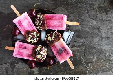 Chocolate And Nut Dipped Cherry Ice Pops On A Plate. Overhead View On A Dark Slate Background.