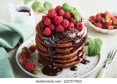 Chocolate Pancakes. Pancakes with fresh raspberry with chocolate glaze or toppings in gray bowl on light gray table background. Homemade classic american pancakes. Page for magazine concept. - Shutterstock ID 2227577053
