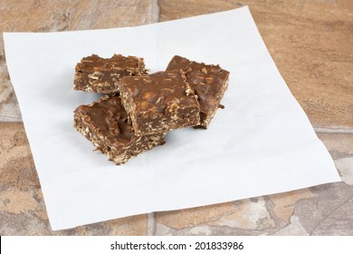 Chocolate peanut butter and coconut no bake snack bars on a parchment paper square.