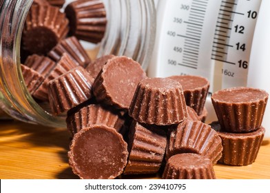 Chocolate Peanut Butter Cups Spilling Out Of A Clear Jar On A Wood Background.