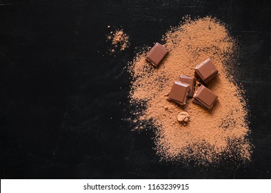 Chocolate pieces and cocoa powder on dark black background. Top view - Shutterstock ID 1163239915