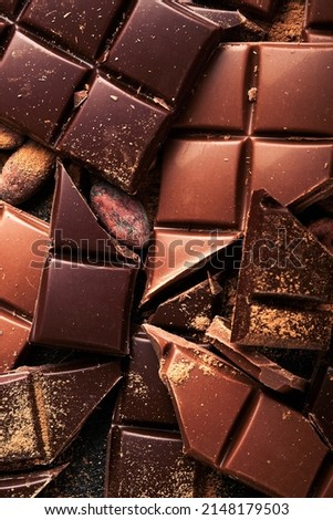Chocolate pieces. Composition of bars and pieces of different milk and dark chocolate, grated and bean cocoa on black background. Baking Chocolate Texture.Top view with copy space. Mock up.