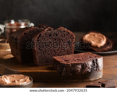 Chocolate pound cake. Loaf of cake sliced into pieces and served with chocolate ganache cream. Brown wooden background. Dark mood. Stock photo © 