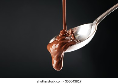 Chocolate Poured On A Spoon On Dark Background