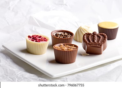 Chocolate pralines assortment on a white background. Selection of finest white, milk and dark chocolate.