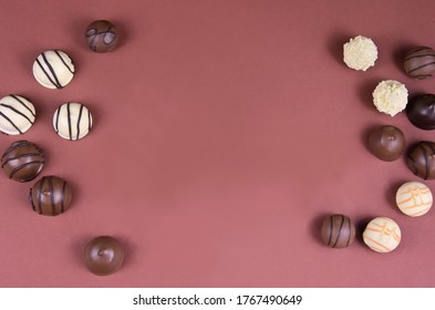 Chocolate pralines frame top view stock images. Chocolate candies on a brown background. Chocolate frame top view. Chocolate pralines background with copy space for text. Border of different candies