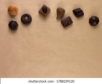Chocolate pralines frame top view stock images. Chocolate candies on a brown background. Chocolate frame top view. Chocolate pralines background with copy space for text. Border of different pralines