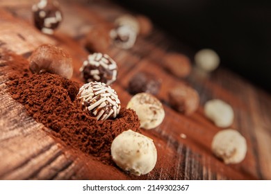 Chocolate pralines, selective focus of chocolate pralines on wooden background with cocoa powder. chocolate concept idea background photo.