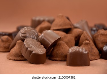 Chocolate pralines and truffles on a brown background stock images. Pile of chocolate truffles and candies isolated on a brown background stock images. Various chocolate candies close-up stock photo