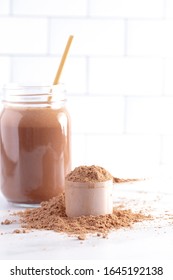 A Chocolate Protein Powder Shake With Straw On A Kitchen Counter