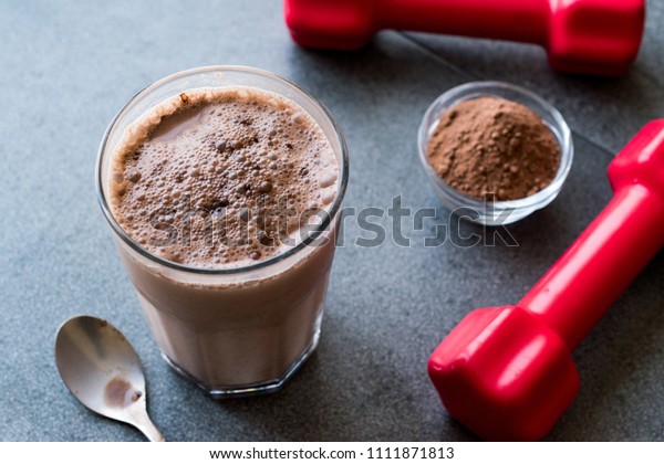 Chocolate Protein Shake Smoothie with Whey\
Protein Powder and Red Dumbbells. Sports\
Drink