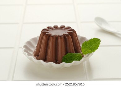 Chocolate pudding with mint leaf, served on a small white plate
