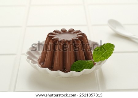 Chocolate pudding with mint leaf, served on a small white plate
