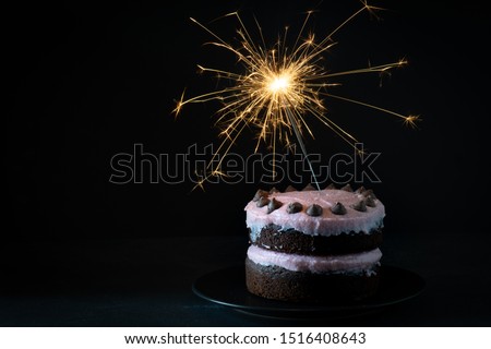 Chocolate and Raspberry Birthday Cake with Sparkler on Dark Background
