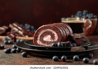 Chocolate roll cake with blueberries and a broken black chocolate bar. - Shutterstock ID 2249563501