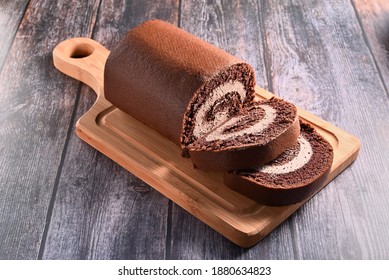 Chocolate roll cake on the wooden cutting board    - Shutterstock ID 1880634823