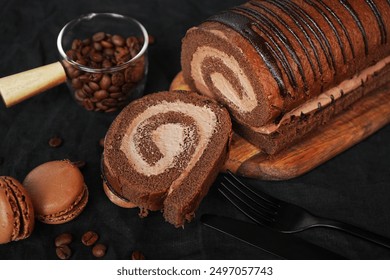 Chocolate roll with chocolate cream next to chocolate macaroons on a wooden board next to coffee beans on a dark background - Powered by Shutterstock