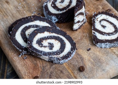 Chocolate Roll With A Creamy Curd Layer In Coconut Chips, A Roll Of Cakes And Cottage Cheese Cut Into Pieces