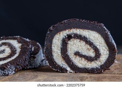 Chocolate Roll With A Creamy Curd Layer In Coconut Chips, A Roll Of Cakes And Cottage Cheese Cut Into Pieces