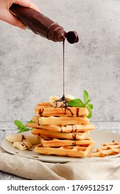 Chocolate Sauce Being Poured Over A Hot, Fresh Stack Of Waffles.