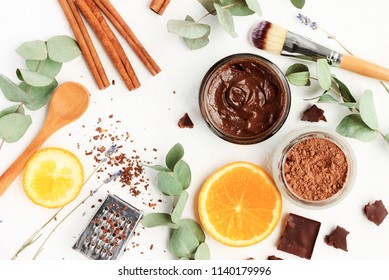 Chocolate Skincare Mask. Natural Ingredients For Making Beauty Treatment Products. Cacao, Orange Slices, Aroma Oil, Jars And Spoons, Herbal Leaves. Top View White Table.