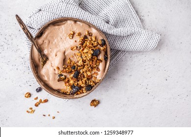 Chocolate smoothie bowl with granola in a coconut bowl, top view. Healthy vegan food concept.