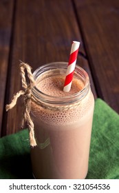 Chocolate smoothie (milkshake) with straw in jar on dark wooden table