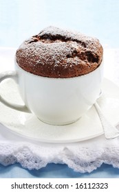 Chocolate Souffle Served In A White Coffee Cup, Dusted With Powdered Sugar.