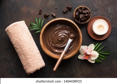 Chocolate Spa flat lay on dark background, top view. Natural chocolate spa beauty products with towel and plants.