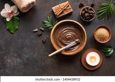 Chocolate Spa flat lay on white background, top view, copy space. Natural chocolate spa beauty products with towel and plants.