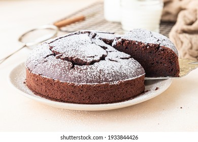 Chocolate sponge flourless cake with sugar powder, light concrete background. Brownie cake. Toned image. Selective focus - Shutterstock ID 1933844426