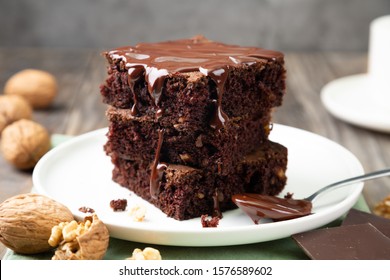 Chocolate spongy brownie cakes with walnuts and melted chocolate topping on a stack 