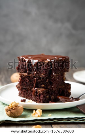 Chocolate spongy brownie cakes with walnuts and melted chocolate topping on a stack 